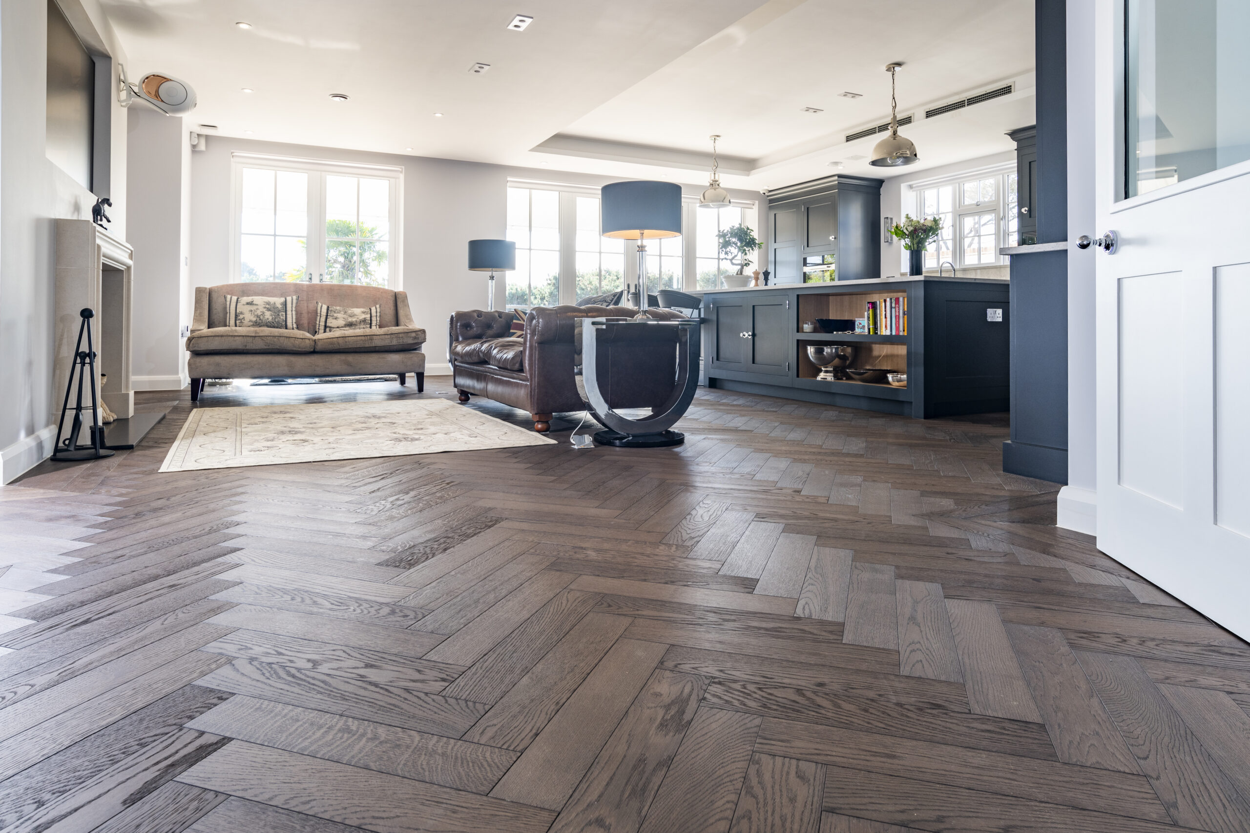 Dark herringbone engineered oak flooring in a luxury open-plan living space